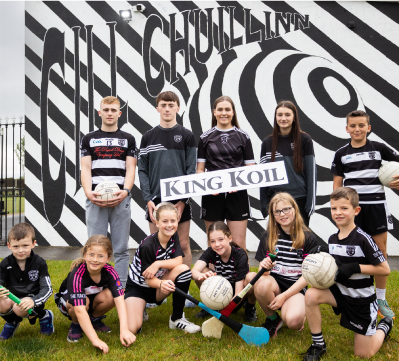 Youth sports team posing with a King Koil banner in front of a mural.