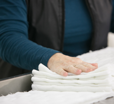 Hand folding white fabric in a textile factory.