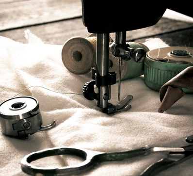 Close-up of a sewing machine stitching white fabric.