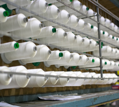 White thread spools arranged on a textile factory rack.