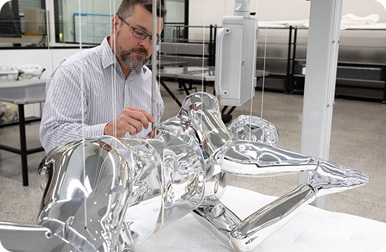 Engineer examining a metallic mattress support component in a testing laboratory