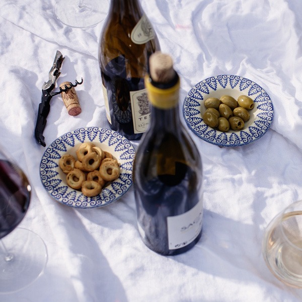a plate of food and wine on a blanket